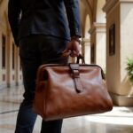 Close-up of leather duffle bag with buckle closure held by traveler, handcrafted brown leather weekend bag