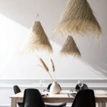 Two handwoven palm leaf pendant lights with bohemian style above minimalist dining room table