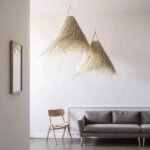 Two handwoven palm leaf pendant lights with conical silhouettes against minimalist white wall