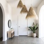 Three handwoven palm leaf pendant lights clustered in modern entryway with wooden console