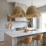 Two handwoven palm leaf pendant lights adding organic warmth above modern marble kitchen island