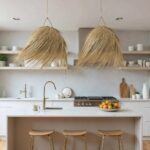 Pair of handwoven palm leaf pendant lights with cascading straw fibers in bright contemporary kitchen
