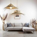 Layered palm leaf pendant light fixtures with organic fringe suspended above contemporary gray sectional sofa