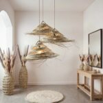 Three graduated palm leaf pendant lights with woven texture and loose fronds in minimalist entryway space