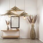 Oversized palm leaf pendant light pair with handwoven tiers and natural fringe above neutral bedroom setting