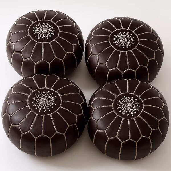 Set of four dark-brown leather pouffe ottoman pieces with white embroidery, viewed from above.