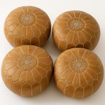 Four camel tan leather floor ottomans with white embroidered stars and geometric stitching, traditional Moroccan craftsmanship