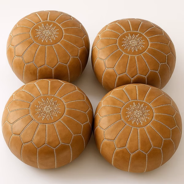 Set of four natural-tan leather pouffe ottoman pieces highlighting hand-stitched panels and medallions.