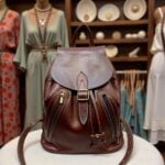Leather backpack brown hanging in vintage room, showing full-grain leather and adjustable drawstrings