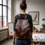 Leather backpack brown with adjustable straps on woman in loft, highlighting premium craftsmanship