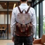 Leather backpack brown worn in office setting, showcasing gray flap and hand-stitched construction