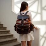 Back view of woman wearing dark brown leather kilim backpack outdoors near stairs showing shoulder straps