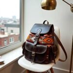 Dark brown leather kilim backpack with geometric patterns on white stool near window with natural light