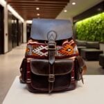 Dark brown leather kilim backpack with handwoven geometric patterns on white pedestal in architectural lobby