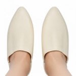 Cream white Moroccan leather slippers worn on feet, handcrafted babouche showing natural leather and pointed toe