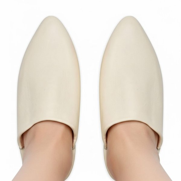 Cream white Moroccan leather slippers worn on feet, handcrafted babouche showing natural leather and pointed toe