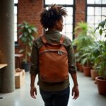 Person wearing brown leather backpack purse in industrial space, unisex handcrafted leather bag