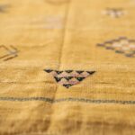 Detailed macro view of cactus silk yellow rug fibers showing natural texture and geometric weaving patterns