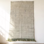 Green cactus silk rug with minimalist design displayed as wall hanging showing natural texture and fringe