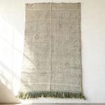 Green cactus silk rug with minimalist design displayed as wall hanging showing natural texture and fringe