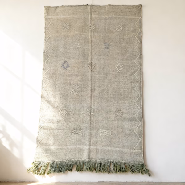 Green cactus silk rug with minimalist design displayed as wall hanging showing natural texture and fringe