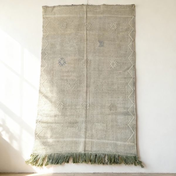 Green cactus silk rug with minimalist design displayed as wall hanging showing natural texture and fringe