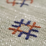 Close-up detail of green cactus silk rug showing colorful geometric embroidered patterns and hand-knotted texture