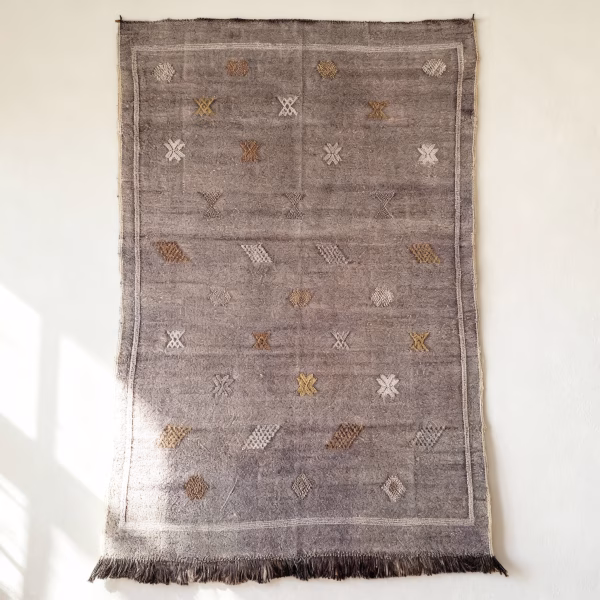 Purple cactus silk rug with geometric diamond patterns displayed as wall hanging showing traditional fringe tassels