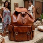 Close-up of brown leather buckle backpack showing antique brass buckles and water-resistant leather texture
