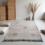 Gray sabra silk cactus rug with diamond patterns on white floor surrounded by meditation cushions
