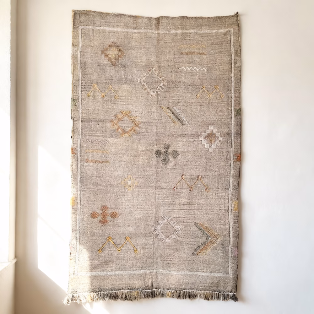 Gray cactus rug with traditional Berber diamond patterns displayed as wall hanging with fringe tassels