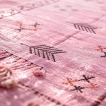 Close-up detail of moroccan sabra rug showing hand-knotted cactus silk texture and geometric motifs