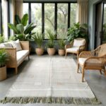 Green Moroccan rug displayed in modern sunroom with natural rattan seating and greenery