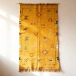 Yellow cactus silk rug wall hanging display showcasing traditional Moroccan tribal patterns and fringe tassels
