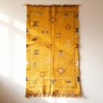 Yellow cactus silk rug wall hanging display showcasing traditional Moroccan tribal patterns and fringe tassels