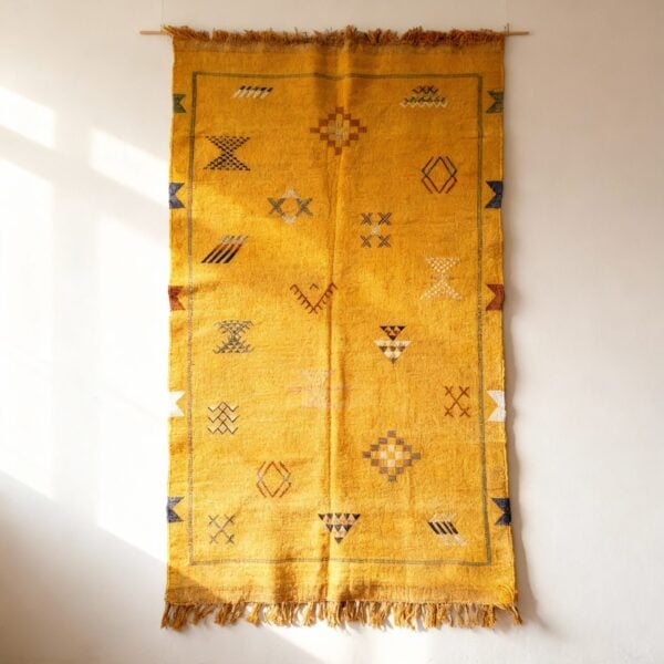 Yellow cactus silk rug wall hanging display showcasing traditional Moroccan tribal patterns and fringe tassels