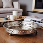 Handcrafted Moroccan silver circle tray with feet styled on wooden coffee table with candles