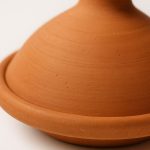 Close-up showing the smooth terracotta surface and turning rings of the tagine clay pot.