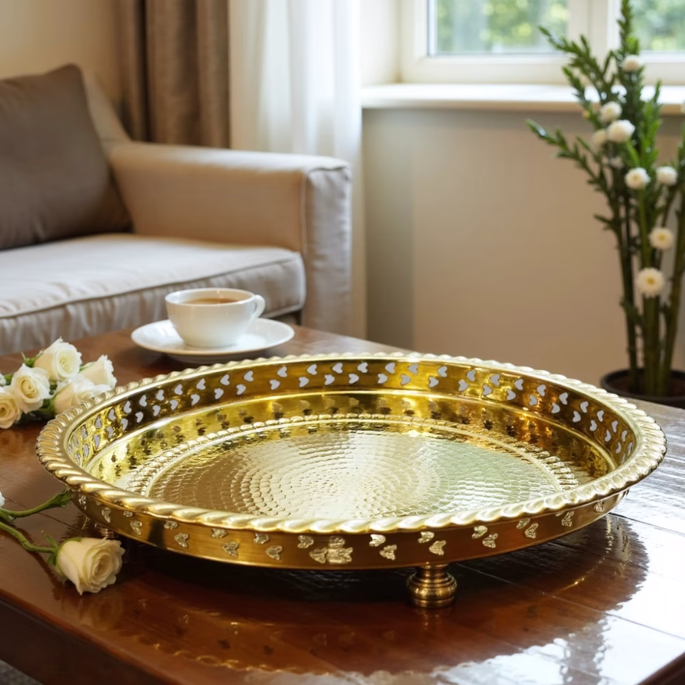 Empty gilt circle tray atop a coffee table beside a sofa and steaming teacup.