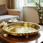 Empty gilt circle tray atop a coffee table beside a sofa and steaming teacup.
