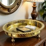 Silver circle tray on entryway console holding stacked notebooks beneath a wall mirror