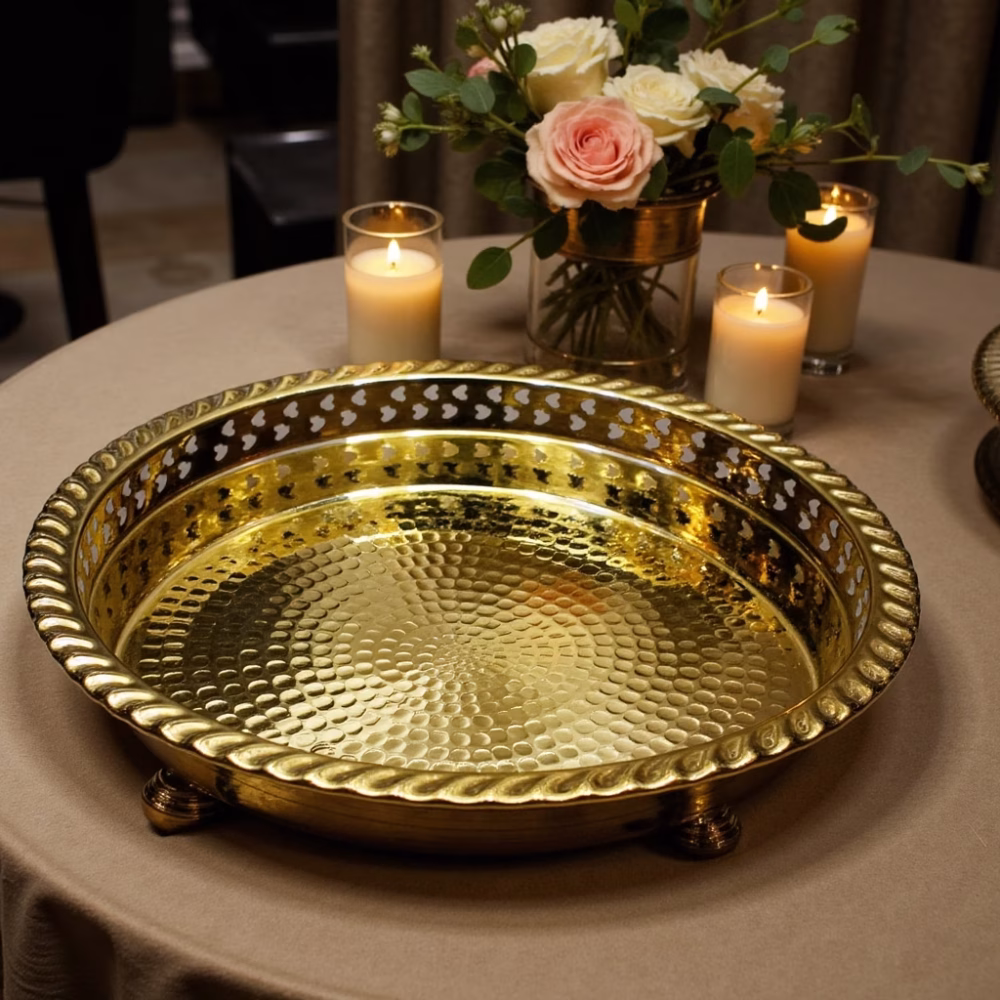 Evening reception table adorned with a gleaming brass circle tray, candles, and roses.