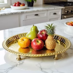 Hammered brass circle tray displaying fresh fruit on a white marble kitchen island.
