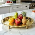Hammered brass silver circle tray holding fresh fruit on a white marble kitchen island