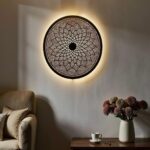 Round brass wall light fixture with detailed geometric cutouts providing soft ambient illumination