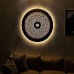 Round brass wall light with pierced floral mandala pattern illuminating contemporary living space