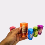 Hand holding orange Moroccan tea glass showing size and detail