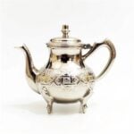 Silver-plated copper moroccan teapot hand-engraved with floral motifs, domed lid, and gooseneck spout on white