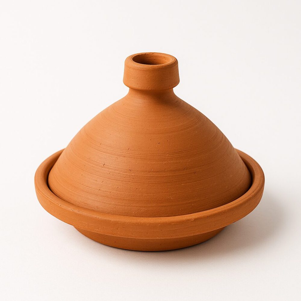 Isolated view of handmade terracotta tagine clay pot with conical lid on white background.