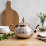 Silver-plated ribbed silver teapot contemporary on wood surface with purple lavender sprigs